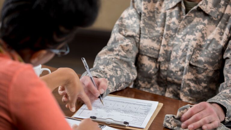 veteran in front of form with a pen in hand