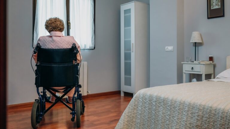Senior woman who uses a wheelchair alone in a room